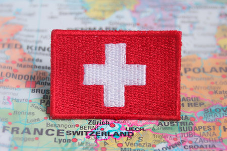 Horizontal eco-themed Swiss flag patch on Europe map, highlighting Switzerland. Great for sustainable tourism, backpacking, and climate-conscious travel projects.の写真素材