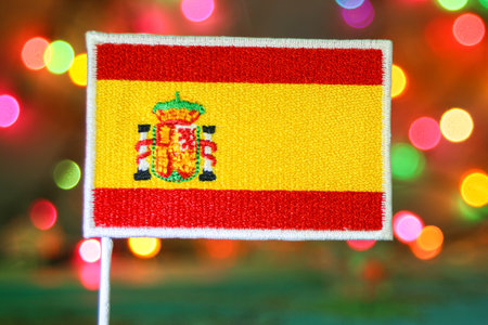 Spain flag embroidery with rainbow bokeh background, representing national holiday celebrations.の写真素材