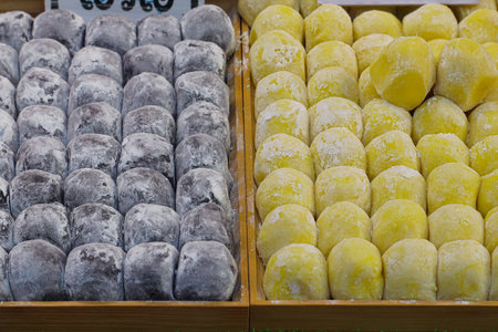Thai mochi dessert variety with chocolate and durian flavors on wooden trays, neatly displayed at a street food stall in Thailand.の写真素材