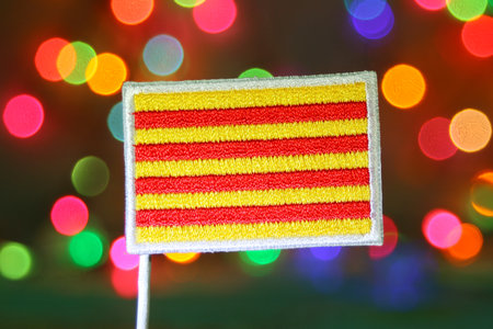 Catalonia flag embroidery with colorful bokeh lights, festive abstract background for Christmas holiday, New Year celebration, culture, and symbolic tradition.の写真素材