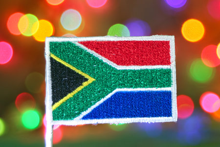 South Africa flag embroidery in front of rainbow bokeh lights, representing festive holidays, Independence Day, and New Year celebrations.の写真素材