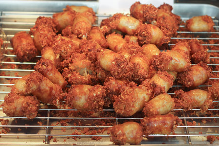 Thai street food Naem sausage, deep-fried until golden and crispy, on tray at vendor stall. Popular tangy snack representing Thailandâs culinary culture.の写真素材