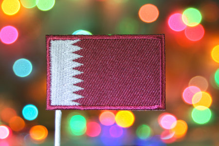 Qatar embroidered flag with rainbow bokeh festive background, resembling fireworks. Symbol of New...