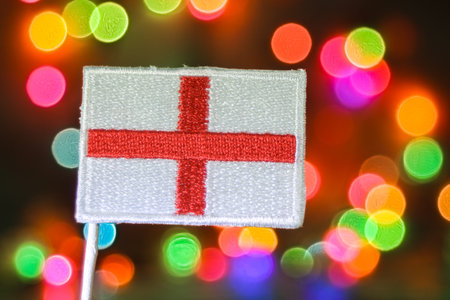 Embroidered Flag of England Saint Georgeâs Cross with colorful bokeh resembling fireworks, perfect for Christmas, New Year, Independence Day, and patriotic holidays.の写真素材