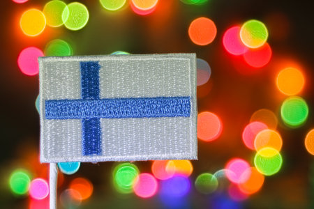 Finland embroidered flag with colorful bokeh fireworks lights, symbolizing Christmas celebration, holiday joy, and patriotic festive atmosphere.の写真素材