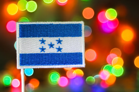Honduras embroidered flag with colorful bokeh fireworks background, symbolizing Independence Day, New Year celebration, and patriotic spirit.の写真素材