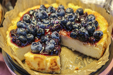 Blueberry cake with shiny jam topping and fresh berries, sliced to show fluffy moist texture, ideal...