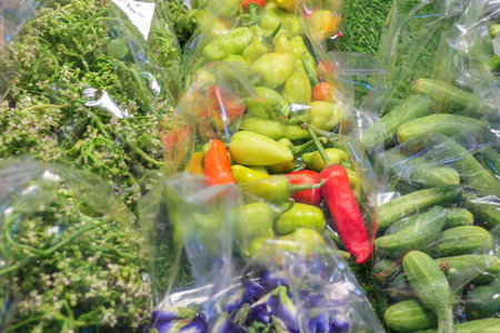 Thai vegetables and herbs sold at local street market, with chili peppers, cucumbers, cowslip...