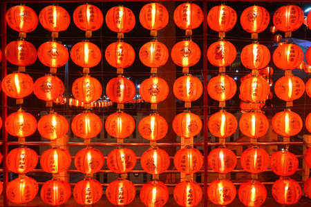 Red Chinese lanterns glowing in rows at night, symbolizing Lunar New Year, cultural traditions, prosperity, and festive celebration atmosphere.の写真素材