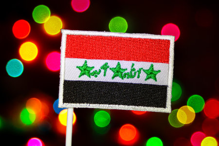 Eye-catching Iraq flag with a sewn finish, on a background of luminous, multi-colored bokeh lights. Ideal for national holidays, unity, and festive visuals.の写真素材