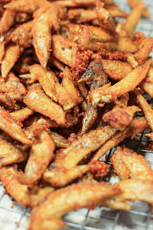 Vertical shot of Deep-fried Chicken Wing Tips on a rack. Golden and crispy, a popular, savory, and easily available Thai street food snack.の写真素材
