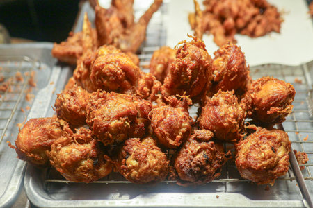 Hat Yai Fried Chicken (Southern Thai style) drumsticks on a metal rack. Golden and crispy, a popular, savory Thai street food snack.の写真素材