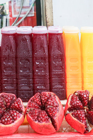 Bottles of cold Pomegranate Juice and Orange Juice at a Thai street market stall. The vibrant color and fresh pomegranate fruit emphasize this popular, natural beverage.の写真素材