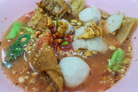 Yentafo (Thai Pink Noodle Soup) served in a bowl with assorted fish balls and crispy toppings. A popular, savory, and tangy Thai street food favorite.の写真素材