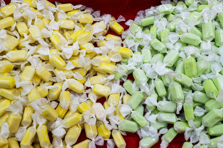 Traditional Thai Toffee (Durian and Pandan) candies, individually wrapped on a red background. A colorful and popular Thai street snack with unique local flavors.の写真素材