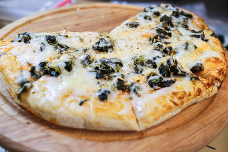 Close-up of a sliced Mushroom Pizza topped with savory Champignon and cheese. A popular, cheesy street food fusion and quick snack on a wooden tray.の写真素材