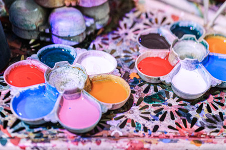 Close-up of a Flower Paint Palette with vibrant watercolor colors. A metallic art supply tool for color mixing, set against a rich, abstract colorful background.の写真素材