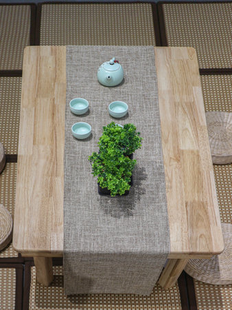 Overhead of a low Japanese tea table setup on a Tatami mat. Ceramic set and faux plant capture a simple, peaceful, and minimalist Zen aesthetic.の写真素材