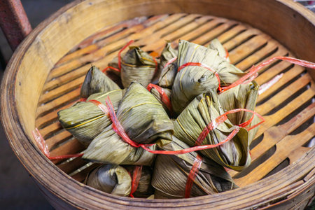 Zongzi (Sticky Rice Dumplings) wrapped and tied, stacked in a bamboo steamer basket. Popular and traditional Thai/Chinese street food snack.の写真素材