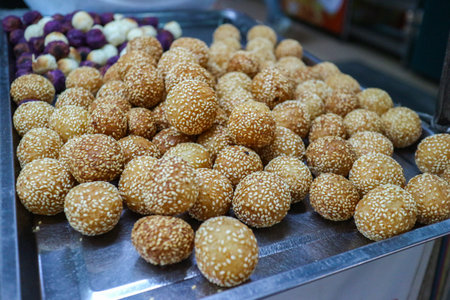 Golden deep-fried Thai Sesame Balls (Ka-nom Kai Hong). The crispy, sweet street food dessert is sprinkled with sesame seeds, showcasing an authentic Asian snack.の写真素材