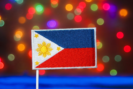 Philippines flag (Sun and Stars) against a vibrant rainbow bokeh background. Represents culture, Independence Day, national day, Christmas, New Year, and festive travel promotion.の写真素材