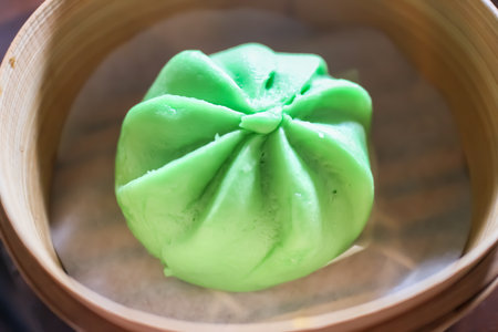 Bright green Pandan/Matcha dim sum buns (Bao) in a bamboo steamer basket. Focus on Asian street food, traditional pastry, and healthy sweet snack concepts.の写真素材