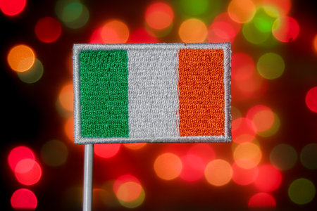 Ireland flag (green, white, orange) against a festive, colorful bokeh background. Represents national pride, Irish culture, and European relations.の写真素材