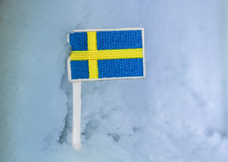 Swedish flag patch placed on glacial snow, capturing Nordic winter travel, Stockholmâs frozen season, climate impact themes, and minimalist Scandinavian identity.の写真素材