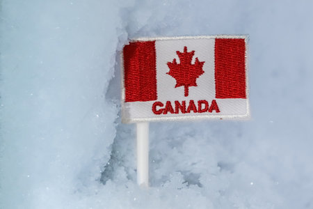 Canadian flag patch embedded in glacial snow, reflecting northern winter tourism, frozen terrain, and the symbolic identity of Canadaâs cold-weather regions.の写真素材