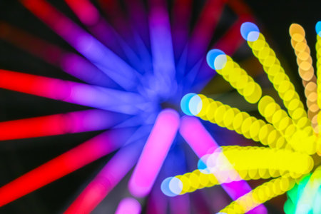 Vibrant abstract motion blur from a night carnival Ferris wheel. Colorful bokeh circles and light trails for festive designs.の写真素材