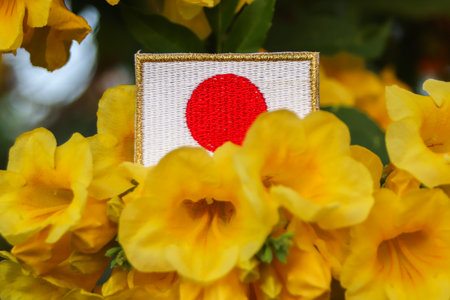 Close up of embroidered flag among bright yellow trumpet flowers, symbolizing mindful design and eco...