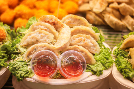Pan gyoza dumplings with golden crispy bottoms served with dipping sauce capturing Asian street food...
