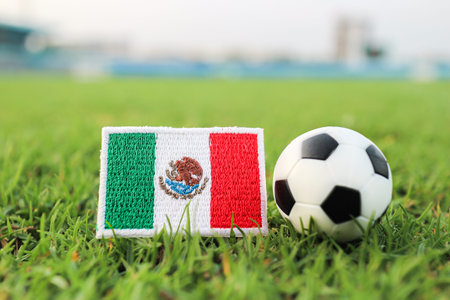 Mexican flag embroidered patch and soccer ball on green grass field representing national pride and international football tournament concept.の写真素材