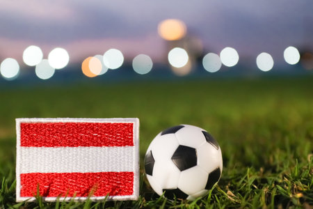 Austria flag and soccer ball on green stadium grass at night with bright arena lights, international football tournament theme.の写真素材