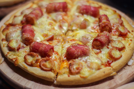 Close up crispy crust sausage and bacon pizza with melted cheese. Comfort street dining concept for menu and marketing use.の写真素材