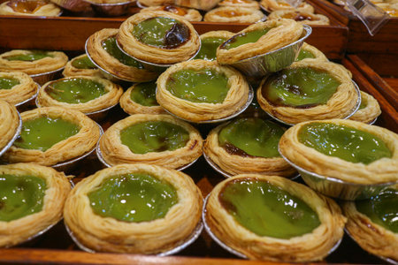 Green tea egg tarts arranged in a pile with crispy pastry and vibrant filling highlighting trendy...