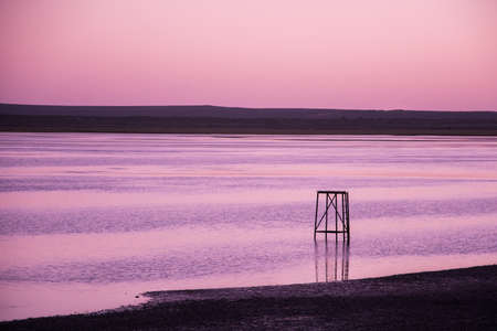 Sunset on the coast with waves and structureの写真素材