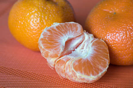 Half of a fresh tangerine on an orange background.の写真素材