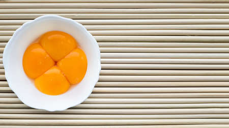 Yellow egg yolks in a white cup, top view.