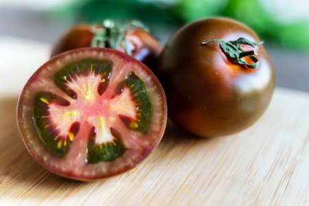 Fresh black tomato kumato on a wooden boardの写真素材