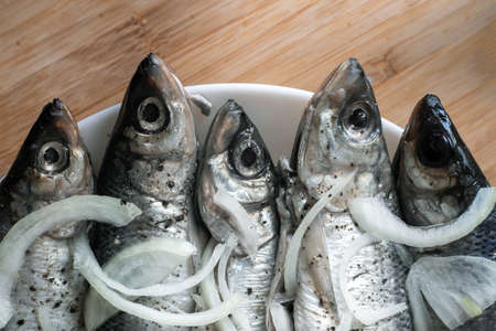 Close-up fish on a plate with onions, background.