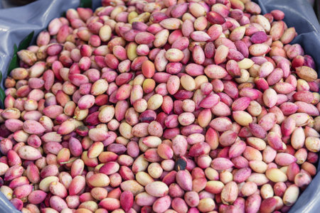 Fresh pink pistachio fruits at a street market., background.