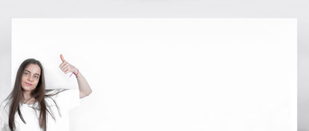 Teenager girl showing a big blank poster shows a thumb up.の写真素材