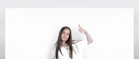 Teenager girl showing a big blank poster shows a thumb up.の写真素材