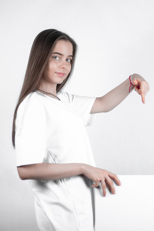 Teenager girl demonstrating a blank sheet of paper shows a thumb down.の写真素材