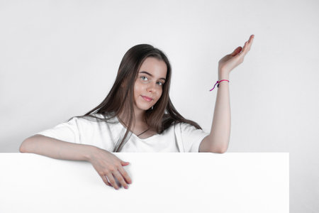 Pointing with her hand to the side, a beautiful woman attracts the eye.の写真素材