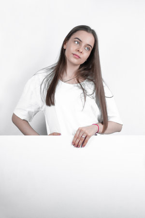 A pretty girl teenager demonstrates with her hands a large white board.の写真素材