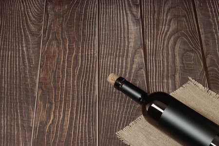 A bottle of wine lies on a background of wooden boardsの写真素材