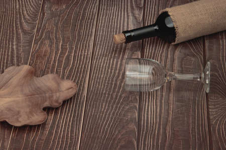 Classic red wine bottle with glass and plate under fruit on conceptual wooden tabletop backgroundの写真素材