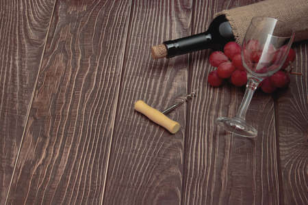 Wine glass and collectible bottle of wine on wooden background with old texture